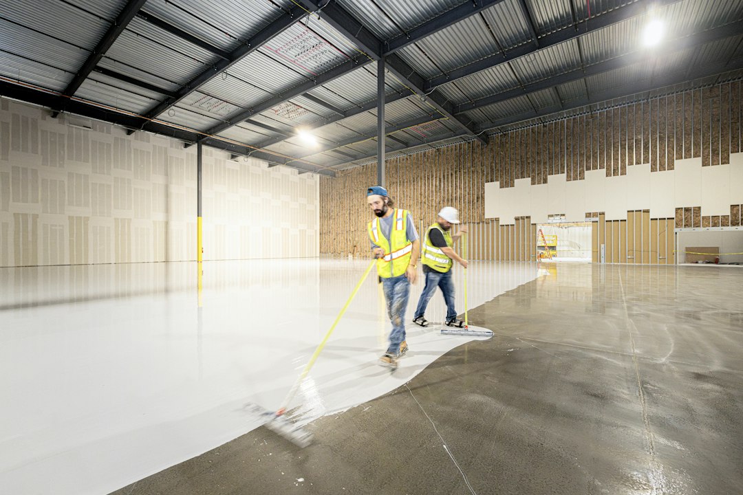 Workers painting the floor of a large empty warehouse in Allen, TX